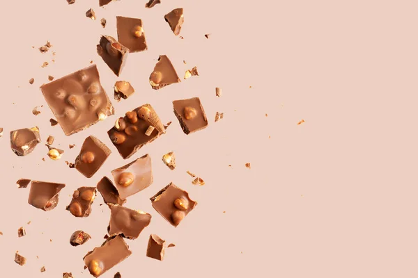 Pile of the chunks of broken different chocolate bars with nuts isolated on white with space for text. Background with chocolate. Sweet food photo concept.