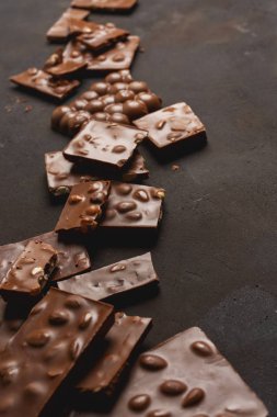 Siyah taş yüzeyinde fındık ve yazı için yeri olan kırık çikolata parçacıkları. Çikolatalı arka plan. Tatlı yemek fotoğraf konsepti.