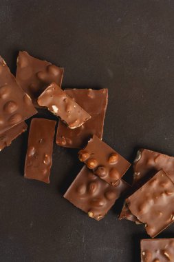 Siyah taş yüzeyinde fındık ve yazı için yeri olan kırık çikolata parçacıkları. Çikolatalı arka plan. Tatlı yemek fotoğraf konsepti.