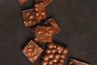 Siyah taş yüzeyinde fındık ve yazı için yeri olan kırık çikolata parçacıkları. Çikolatalı arka plan. Tatlı yemek fotoğraf konsepti.