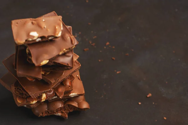 Pile of the chunks of broken different chocolate bars with nuts, whisper, bubble