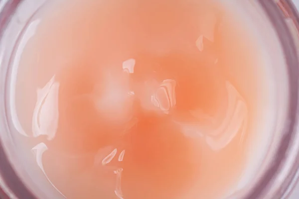 Texture of liquid cream in a pink jar. Cosmetic background. Macro.