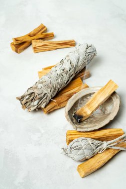 Smudge kit for spiritual practices with natural elements: Palo Santo sticks, dried white sage, Guinea Fowl feather, crystals, sea pearl shell Abalone on a light background. Balancing the soul.