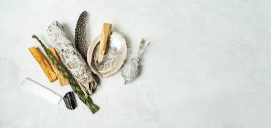 Smudge kit for spiritual practices with natural elements: Palo Santo sticks, dried white sage, Guinea Fowl feather, crystals, sea pearl shell Abalone on a light background. Balancing the soul.