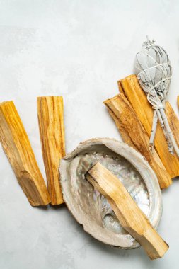 Smudge kit for spiritual practices with natural elements: Palo Santo sticks, dried white sage, Guinea Fowl feather, crystals, sea pearl shell Abalone on a light background. Balancing the soul.