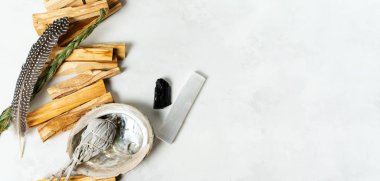 Smudge kit for spiritual practices with natural elements: Palo Santo sticks, dried white sage, Guinea Fowl feather, crystals, sea pearl shell Abalone on a light background. Balancing the soul.