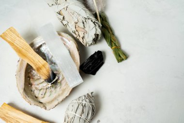 Smudge kit for spiritual practices with natural elements: Palo Santo sticks, dried white sage, Guinea Fowl feather, crystals, sea pearl shell Abalone on a light background. Balancing the soul.