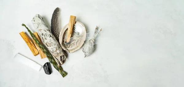 Smudge kit for spiritual practices with natural elements: Palo Santo sticks, dried white sage, Guinea Fowl feather, crystals, sea pearl shell Abalone on a light background. Balancing the soul.