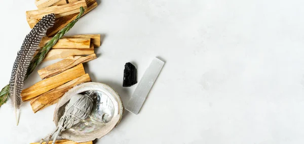 Smudge kit for spiritual practices with natural elements: Palo Santo sticks, dried white sage, Guinea Fowl feather, crystals, sea pearl shell Abalone on a light background. Balancing the soul.