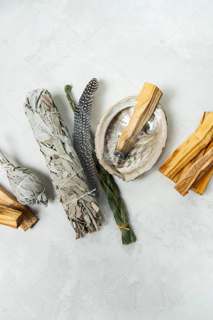 Smudge kit for spiritual practices with natural elements: Palo Santo sticks, dried white sage, Guinea Fowl feather, crystals, sea pearl shell Abalone on a light background. Balancing the soul.