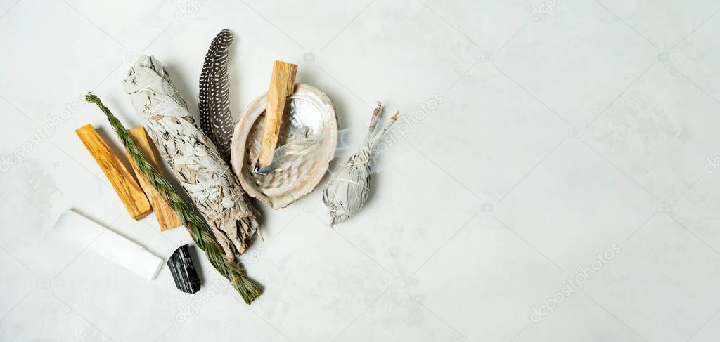 Smudge kit for spiritual practices with natural elements: Palo Santo sticks, dried white sage, Guinea Fowl feather, crystals, sea pearl shell Abalone on a light background. Balancing the soul.