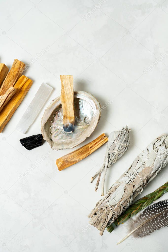 Smudge kit for spiritual practices with natural elements: Palo Santo sticks, dried white sage, Guinea Fowl feather, crystals, sea pearl shell Abalone on a light background. Balancing the soul.