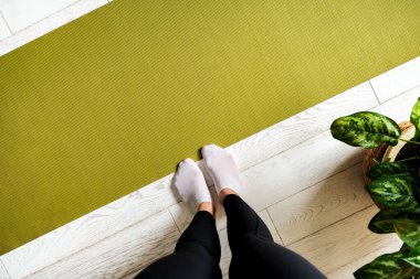 Egzersiz paspasındaki kadın bacakları. Evde yoga yapmaya hazırlanıyorum. Yoga yapan bir kadın.. 