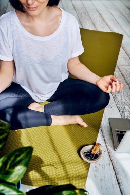 Evde karantinada yoga yapan bir kadın. Ulusal yoga günü. Kilit altında sağlıklı bir yaşam. Meditasyon palo santo çubukları kullanılıyor..