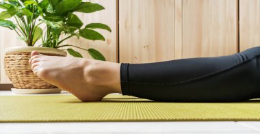 Egzersiz minderinde kadın bacaklarına yakından bak. Evde yoga yapmaya hazırlanan bir kadın. Ulusal yoga günü. Sağlıklı yaşam tecrit altında.