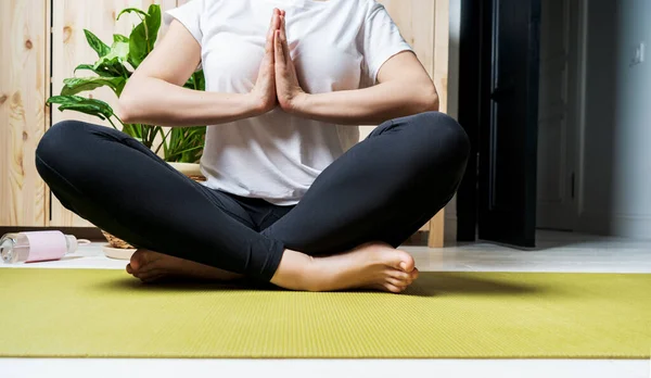 Woman legs on Lotus position on an exercise mat. Female preparing practicing yoga at home. National yoga day. Healthy living in lockdown.