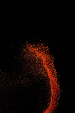 Red paprika spices powder explosion, flying chili pepper isolated on black background. Splash of spice background.  clipart