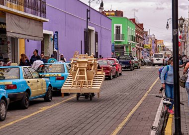 Sanatçı San Pedro Cholula caddesinde el arabasıyla mobilya taşır..
