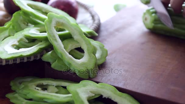 Out of focus view of cook's hands slicing bitter gourd with a Japanese gyuto — Stock Video