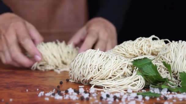 De fokuserade utsikt över en Cooks hand prepping en rulle av Ramen innan han skålla det i varmt kokande vatten — Stockvideo