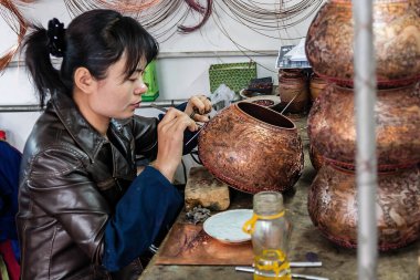 Bakır vazo oyan genç bir Çinli kadın işçi.