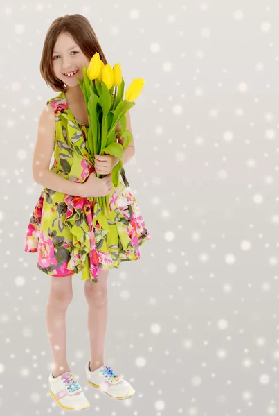 Petite fille avec un bouquet de tulipes jaunes . — Photo