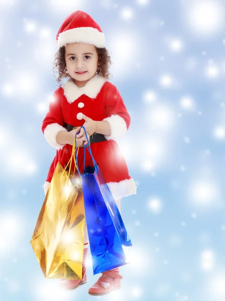 Маленькая девочка в костюме Санта-Клауса с красочными пакетами — стоковое фото