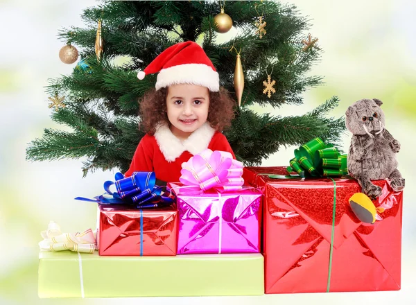 Маленька дівчинка біля ялинки в оточенні подарунків — стокове фото