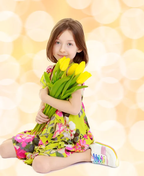 Kleines Mädchen mit einem Strauß gelber Tulpen. — Stockfoto
