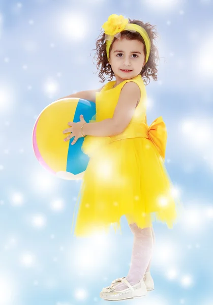 Little girl in yellow dress holding a ball — Stock Photo, Image