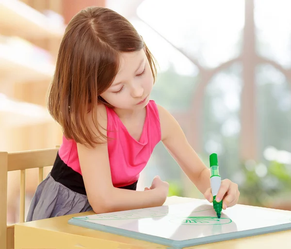 Meisje trekt met de markeerdraad aan de tafel. — Stockfoto