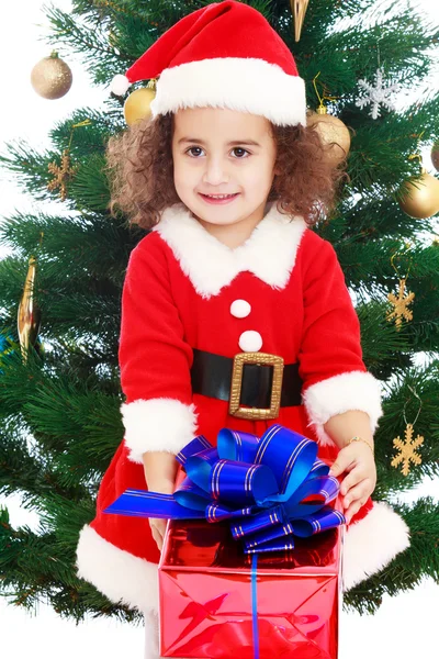 Petite fille près du sapin de Noël avec un cadeau dans ses mains — Photo