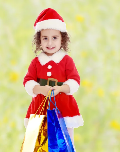 Little girl in costume of Santa Claus with colorful packages — Stock Photo, Image