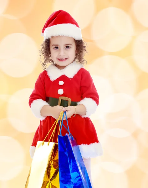 Menina em traje de Papai Noel com pacotes coloridos — Fotografia de Stock