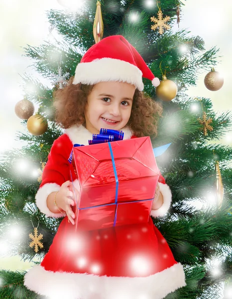 Little girl near the Christmas tree with a gift in its hands Royalty Free Stock Images