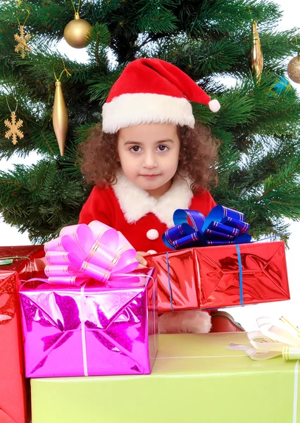 Malá holčička blízko vánočního stromku obklopená dárky — Stock fotografie