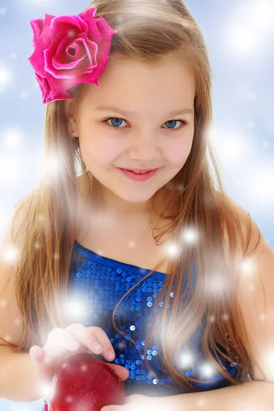 Küçük kız ellerinde kırmızı elma tutar.