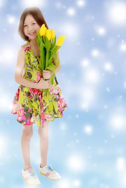 Petite fille avec un bouquet de tulipes jaunes . — Photo