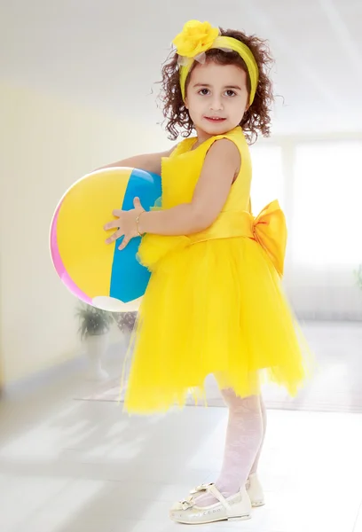 Klein meisje in gele jurk houden van een bal — Stockfoto