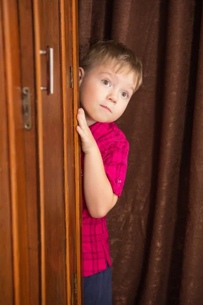 Мальчик спрятался за шкафом. — стоковое фото