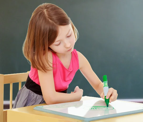 Malá holčička kreslí značky u stolu. — Stock fotografie
