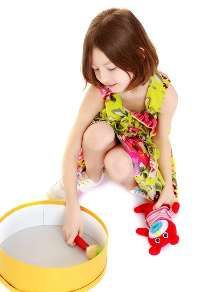 Kleines Mädchen spielt mit einer runden Schachtel. — Stockfoto