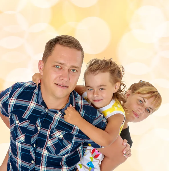 Mom and daughter look out from behind dad — Stock Photo, Image