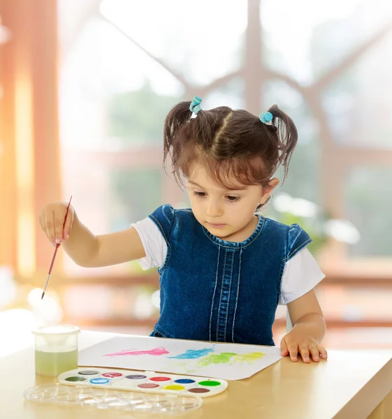 Niña pinta con acuarelas en la mesa . — Foto de Stock