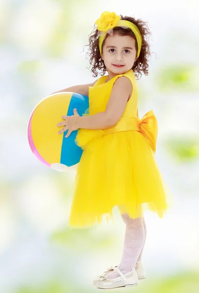 Bambina in abito giallo con una palla in mano — Foto Stock