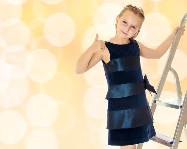 Little girl stands on the stairs and shows thumb. — Stock Photo, Image