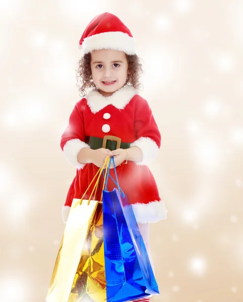 Menina em traje de Papai Noel com pacotes coloridos — Fotografia de Stock