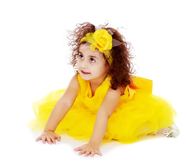 Little girl in yellow dress sitting on the floor — Stock Photo, Image