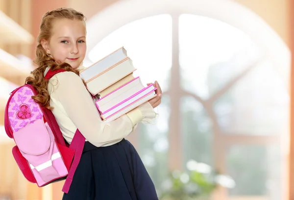 Chica colegiala con una cartera detrás de los hombros y libros en han — Foto de Stock