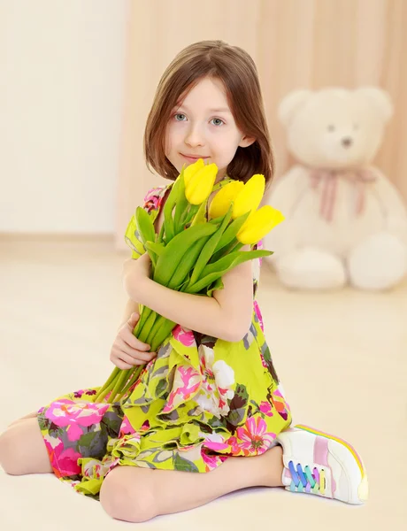 Kleines Mädchen mit einem Strauß gelber Tulpen. — Stockfoto